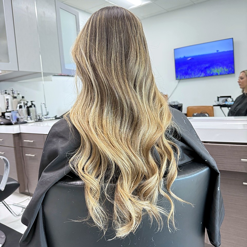 Long, sun-kissed blonde balayage styled at Hello Gorgeous Hair Lounge in Frisco, Texas